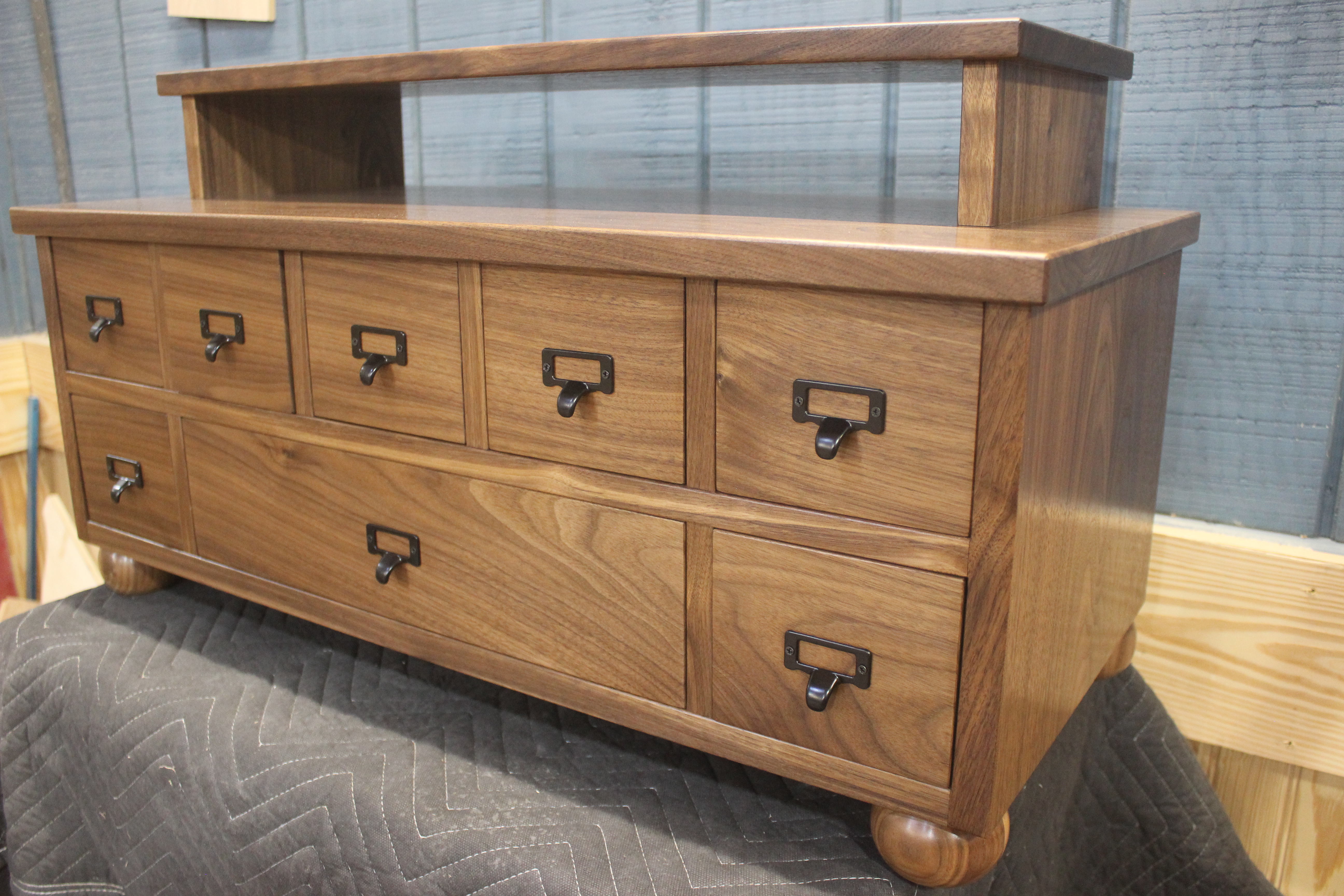A wooden storage cabinet with eight drawers, featuring a smooth top surface and black metal handles.