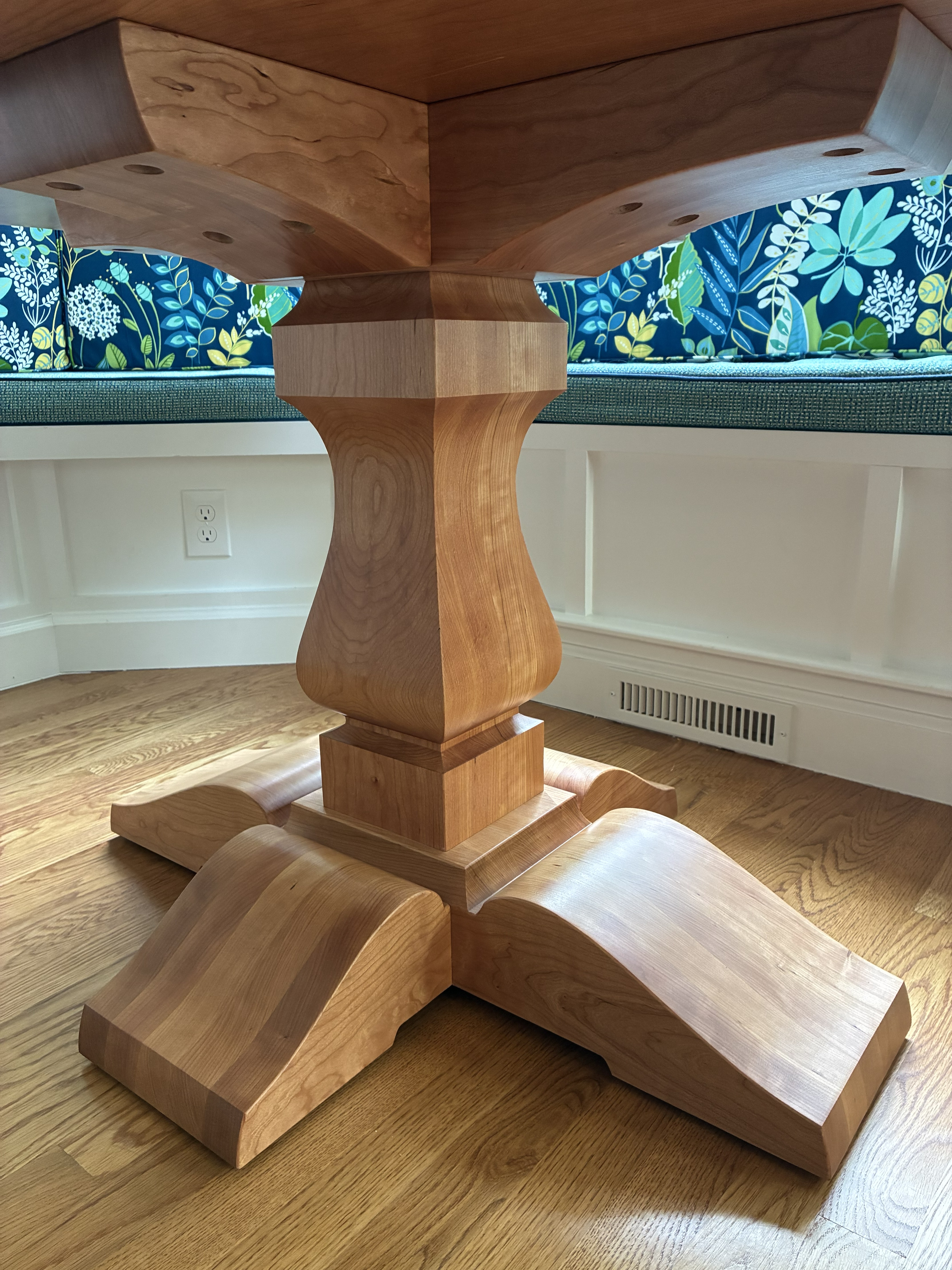Close-up view of a wooden table's intricately designed base, showcasing its smooth finish and detailed craftsmanship.